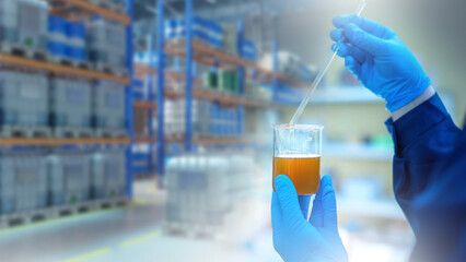 Laboratory testing of fuel. Hands of laboratory assistant near blurred warehouse. Flask with fuel for analysis. Checking gasoline quality. Analysis of fuel for octane number. Gasoline quality control