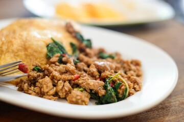 A plate of pad kra pao (holy basil pork mince stir-fry) with omelette and mixed grain rice, and...