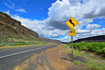 An asphalt road with a 40 mph speed limit sign and a curve warning sign