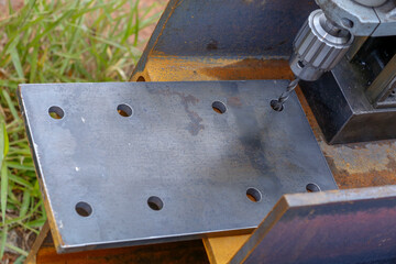 metal drill bit make holes in steel billet on industrial drilling machine. Metal work industry.