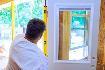 Installing front door of new house, carpenter uses yellow spirit measure level