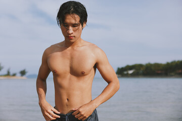 Sun-kissed Asian Man Tanning on a Tropical Beach, Enjoying the Freedom and Happiness of a Summer Vacation