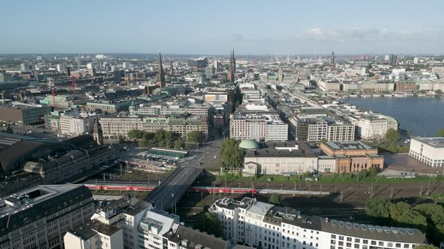 Aerial panorama view of the Hamburg skyline, Germany. The city is seen from above with dense urban development, modern and historic buildings, and wide streets stretching toward the horizon. This pano
