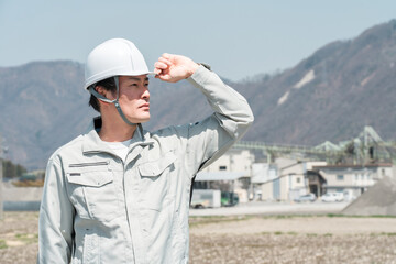 ヘルメットを被った作業着姿のアジア人男性作業員
