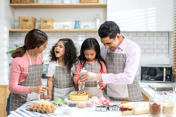 Portrait of enjoy happy love asian family father and mother with little asian girl daughter child play and having fun cooking food together with baking cookie and cake ingredient in kitchen