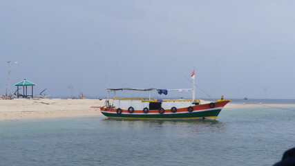 Naklejka premium Colorful Fishing Boat Near Sandy Beach and Gazebo
