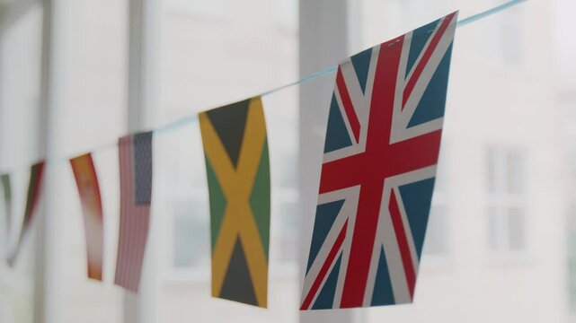 Close-up no people shot of country flags of UK, USA, Brazil, Spain hanging on string, decorating windows in language school class