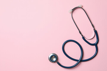 Stethoscope on pink background, top view. Space for text