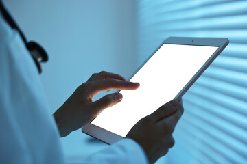 Doctor using tablet in hospital at night, closeup