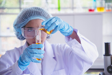 Scientist woman holding chemical test yellow glass tube testing science laboratory. Lab technician...