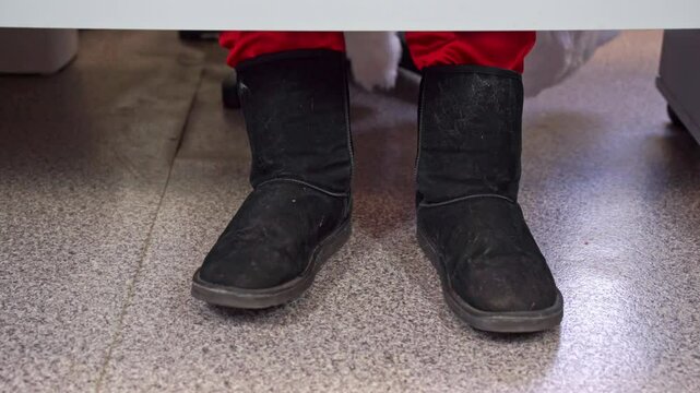 Impatient man sits in line, waits excitedly, shakes leg, beats rhythm on floor, close-up warm suede ugg boots Emotions of anxiety, stress response, unconscious leg movement, shaking, dancing to music 