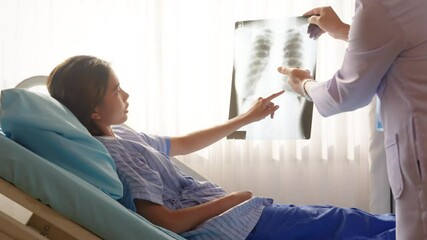 Specialized hospital medical service center and health care insurance concept. Asian male doctor examine, explaining x-ray results and assessment illness symptoms to patient in hospital recovery room.