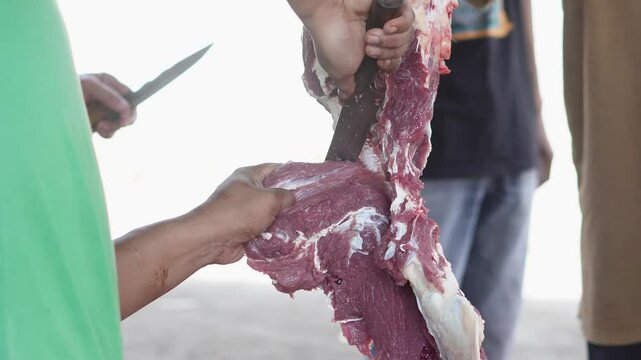 Close-up 4K footage of a Muslim male butcher cutting goat meat to distribute to Muslims in need during Eid al-Adha Al Mubarak