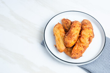 Fried Banana served on a white plate. Indonesian food. Indonesian street food. Perfect for recipe, article, catalogue, commercial, or any cooking contents.