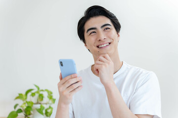 リビングで携帯を見る笑顔の私服の男性