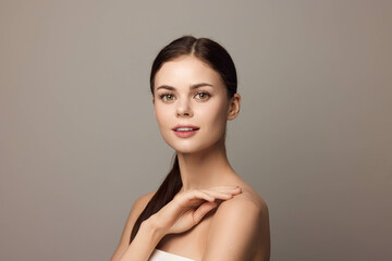 Beautiful young woman with hands on her chest posing and looking at the camera, on a gray background