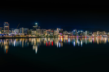  Illuminated central city buildings in downtown Wellington, New Zealand reflected in the calm water of harbour before dawn.