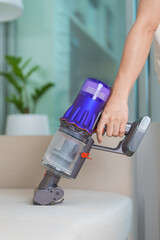 Woman cleaning Sofa with cordless Vacuum cleaner. Housewife using wireless Vacuum for big cleaning home. Housework, Housecleaning, Housekeeping, Removes dust, Domestic hygiene and daily routine