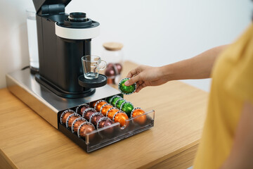 hand making Espresso Coffee by Coffee Maker Machine with Capsule of roasted coffee bean on wood table bar. Daily beverage drink at Home, Apartment and Office concept