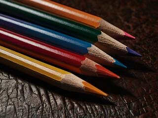 Fototapeta premium Colored Pencils on Leather: A close-up of brightly colored pencils arranged in a grid pattern on a smooth, dark leather surface, highlighting the contrast between the materials.