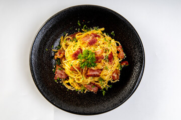 Spaghetti Carbonara in black plate on white background