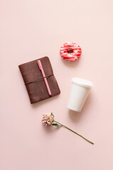 Feminine desk, top view. Flower, planner paper coffee cup and donut.