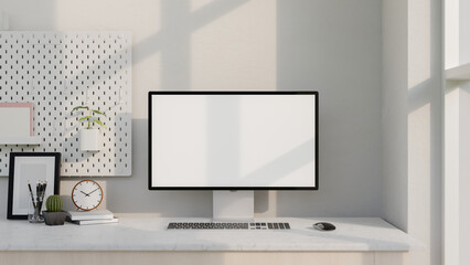 A modern white computer desk features a computer with a white-screen mockup and decor.