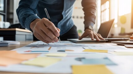 Focused on the Goal: A businessman meticulously analyzes data and charts, surrounded by sticky notes and a laptop, showcasing his dedication to strategic planning and problem-solving.  