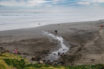 Holidaymakers relaxing on the black sand beach of  Muriwai, Auckland, New Zealand.