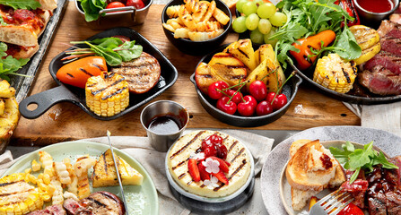 Table with grilled food. Pizza, corn, tomatoes, peppers, cooked meat. BBQ time