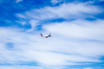 Airplane Flying High in a Clear Blue Sky with White Clouds