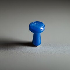 A single blue push pin or thumbtack placed at the center of an empty plain white or gray background  The push pin stands out against the minimalist simple backdrop creating a clean geometric
