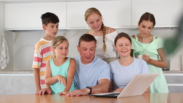 Big tight-knit friendly family getting together at kitchen for making video call 