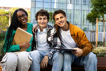 Multiracial college students sitting on campus bench looking at camera. Copy space.