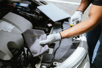 A technician in a workshop uses a wireless device to check a car's condition, updating a digital...