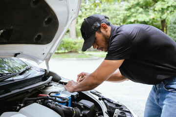 A technician examines a car engine in a garage, focusing on battery and electrical components. The close-up scene emphasizes quality control, maintenance, and automotive expertise.