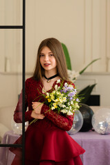 Teen girl in red lace dress holding bouquet of flowers