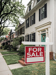 Fototapeta premium A “FOR SALE” sign displayed before a home in a residential area