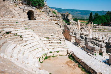 Ancient stone amphitheater ruins with a backdrop of green hills. This image captures the historical...