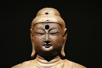 Close up Buddha face statue isolated on black background. Bronze Buddha statue portrait.