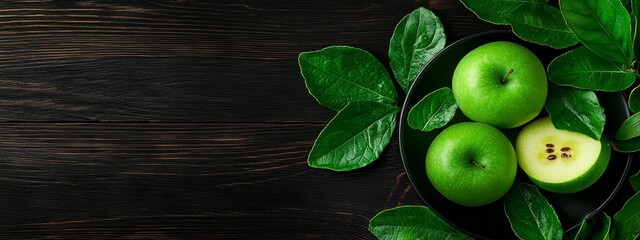  A dark wooden table bears a platter of green apples, their leaves included, offering ample room for text or an insert