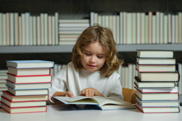 Serious school boy. School boy reading book in library. Kids development, learn to read. Pupil reading books in a book store.