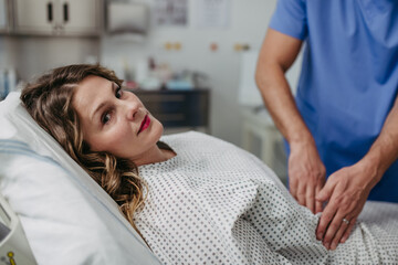 Doctor palpating woman's abdomen, using hands and steady pressure.