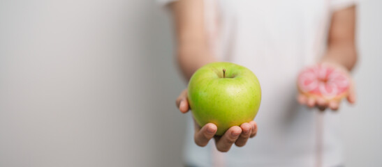 woman hand hold green Apple and donut, female fitness choose between fruit is Healthy and sweet is...