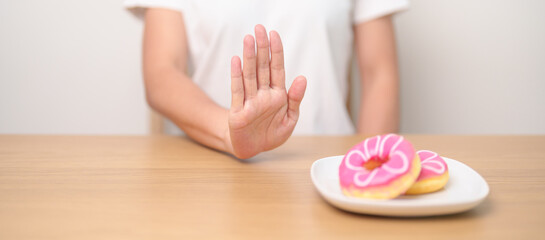 woman hand reject donut dessert, female refuse Unhealthy junk food. Dieting control, Weight loss, Obesity, eating lifestyle and nutrition concepts