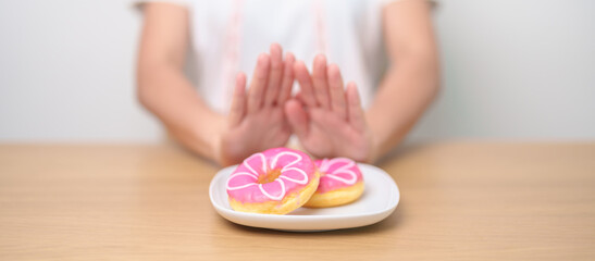 woman hand reject donut dessert, female refuse Unhealthy junk food. Dieting control, Weight loss, Obesity, eating lifestyle and nutrition concepts