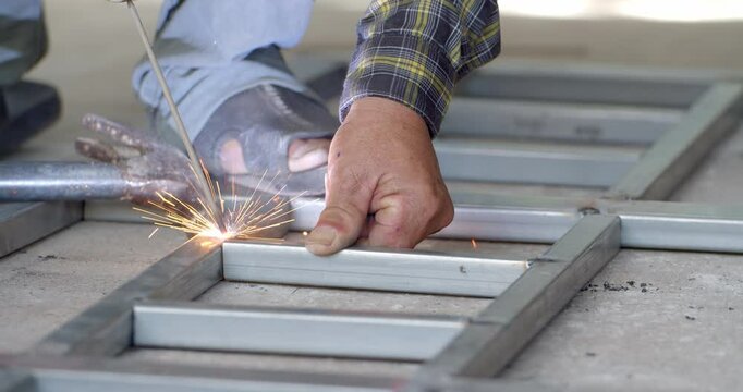 Tap the welded steel with a hammer to make the workpiece exactly as desired.Male hands welding metal pieces together.