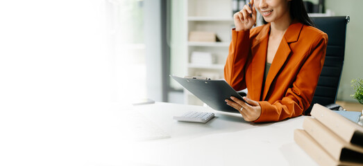 Asian woman sitting at a desk using a laptop computer Navigating Finance and Marketing