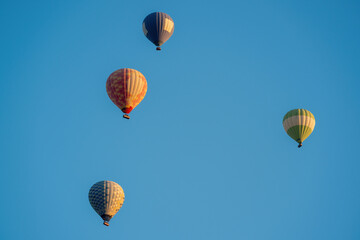 Fototapeta premium Hot air balloons in dark blue, red and yellow colors flying in a slightly cloudy blue sky