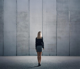facing obstacles - woman is standing in front of concrete wall
